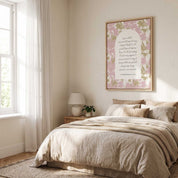 Framed Christian floral wall art titled 1 Corinthians 13:4–8 featuring "Love is patient, love is kind" with watercolor florals, displayed on a beige wall above a bed in a cozy, sunlit bedroom.