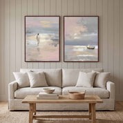 Pair of framed Christian seascape prints showing a shore figure and sailboat, displayed above a beige sofa in a warm neutral living room.