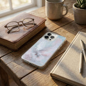 Phone with a floral case on a wooden table with books, glasses, and a mug.