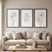 A three-piece Christian gallery wall set featuring minimalist black line art on neutral beige backgrounds. The center print displays "The Lord bless you and keep you" from Numbers 6:24-26 in elegant typography, flanked by a lily line drawing on the left and a poppy line drawing on the right, all in black frames above a beige sofa.