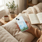 Person holding a phone with a nature-themed case on a cozy couch with a book and cup of tea.