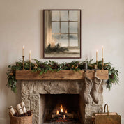 Vintage Christian Christmas candle artwork above a stone fireplace with evergreen mantel garland, brass candlesticks, and stockings.