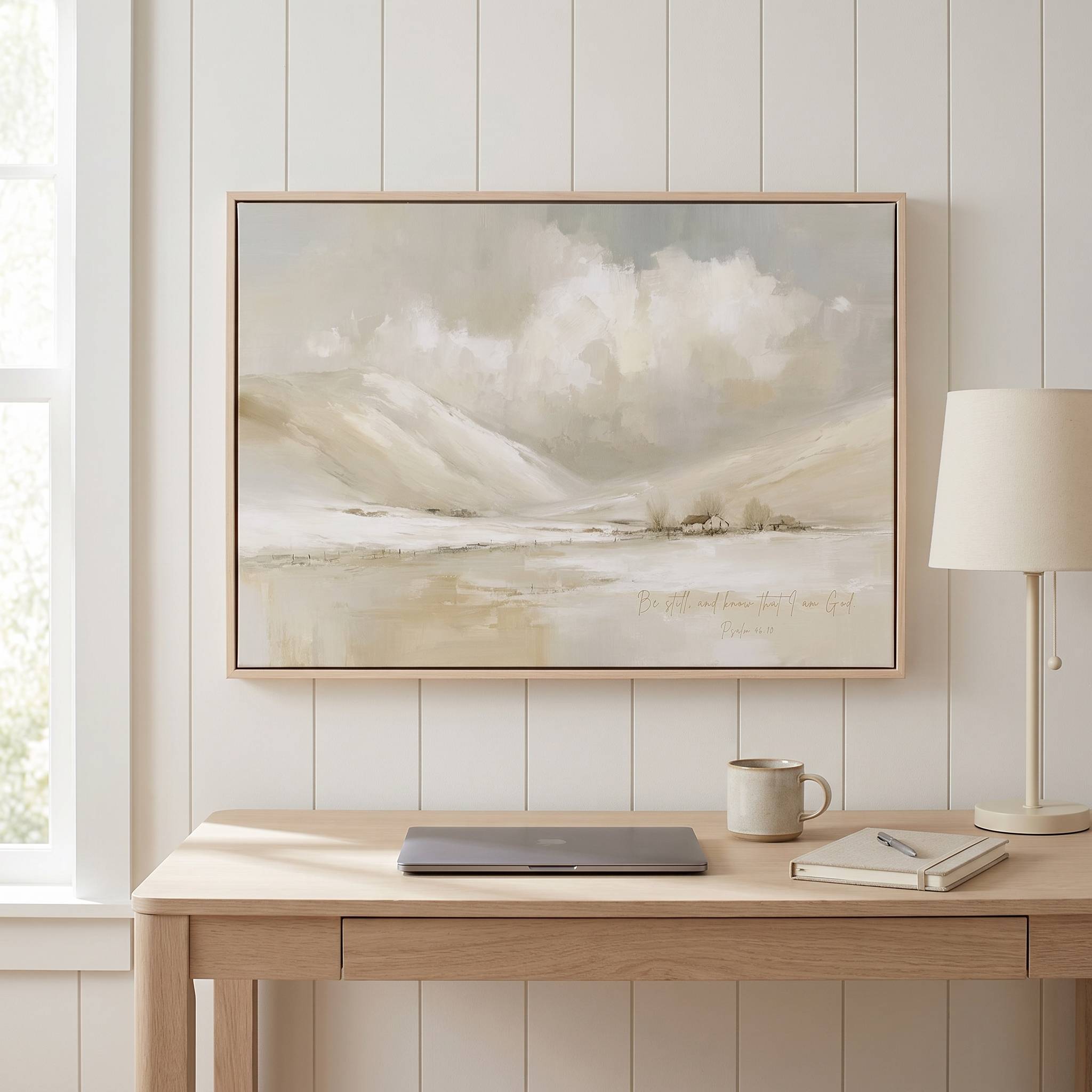 Framed vintage Christian winter landscape wall art titled Be Still and Know with Psalm 46:10 verse, displayed on a white paneled wall above a light wood desk in a modern home office.