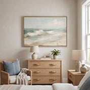 Framed vintage Psalm 46:10 Christian landscape canvas wall art featuring a coastal beach scene hanging on a beige wall above a light wood dresser in a styled bedroom with a wicker armchair.