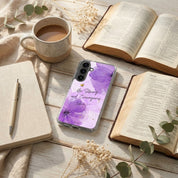 Christian Samsung phone case with purple design on a wooden surface with books and a cup of coffee.