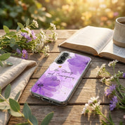 Christian Samsung phone case with purple floral design on a wooden table with flowers and an open book.