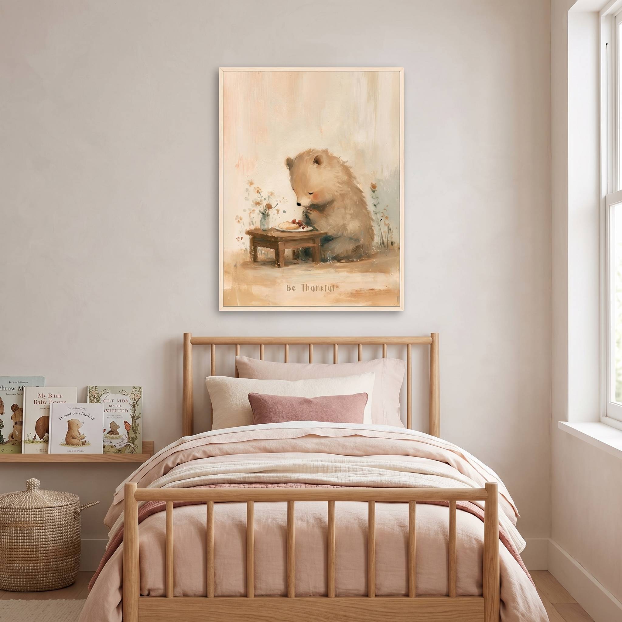 Framed Be Thankful praying bear Christian kids wall art above a wooden bed with blush bedding, beside children’s books in a soft neutral bedroom.