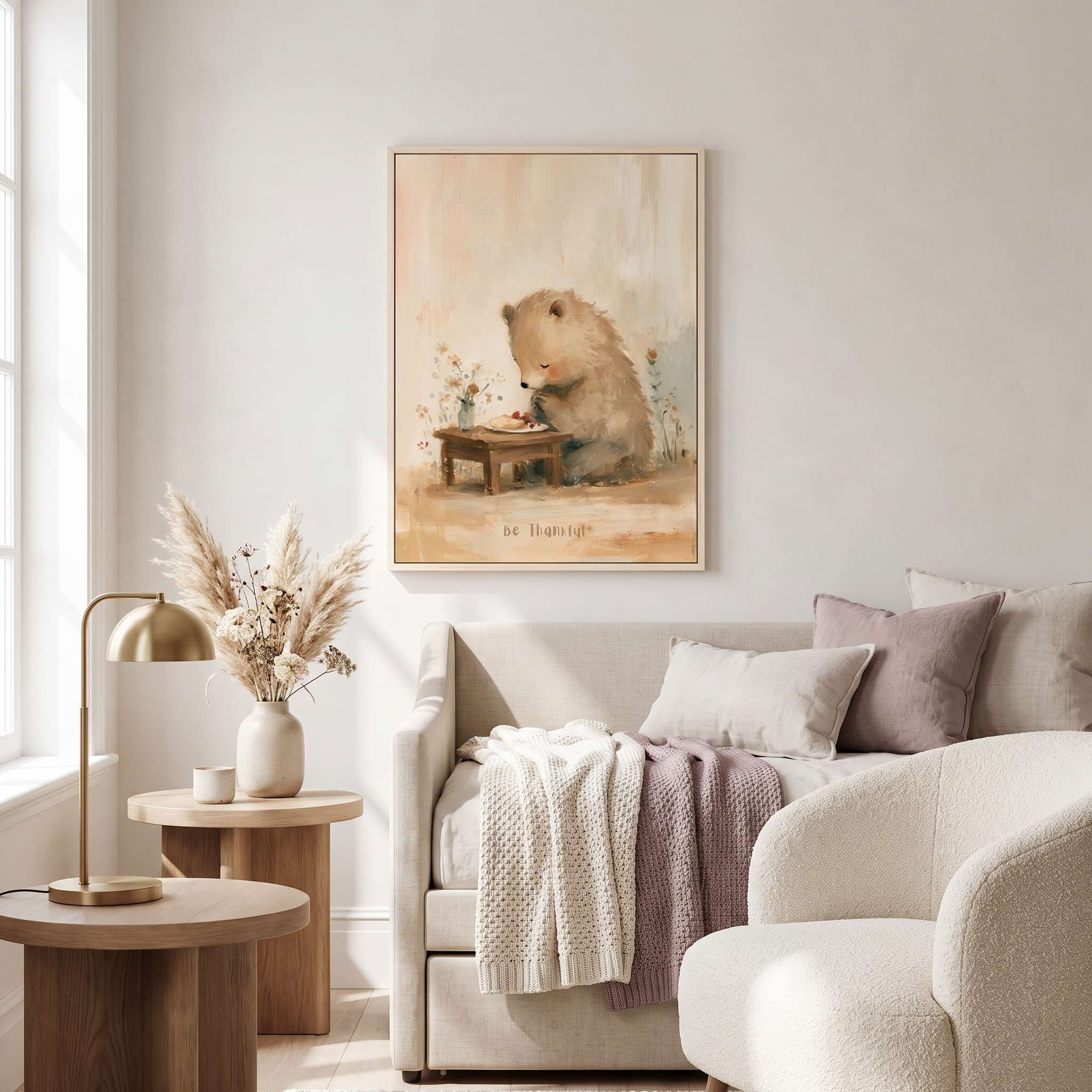 Framed Be Thankful praying bear Christian wall art above a cream sofa, styled with blush cushions and neutral decor in a sunlit living room.