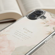 Ultra close-up of By Grace Through Faith MagSafe® clear iPhone case featuring elegant blush floral artwork and Ephesians 2:8 scripture in a soft neutral Christian aesthetic setting