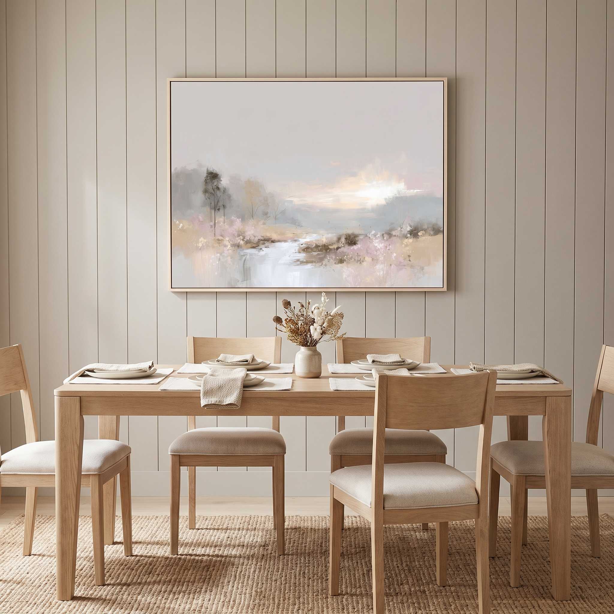 Framed Christian landscape wall art of a serene lake and soft sky, displayed on a light wood paneled wall above a dining table and chairs.