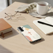Christian cross Samsung phone case with minimalist beige botanical design on desk with Bible coffee mug notebook and glasses in soft natural light symbolizing faith in Jesus Christ