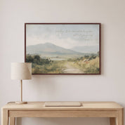 Framed vintage Christian landscape wall art titled Come to Me with Matthew 11:28 verse, displayed above a light wood desk with a table lamp in a modern home office.