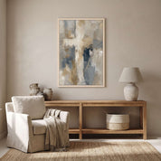 Framed contemporary abstract cross canvas wall art hanging above a light wood console table beside a linen armchair in a bright living room.