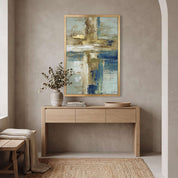 Contemporary Christian abstract cross framed canvas wall art in gold frame displayed on a beige wall above a light wood console table in an organic modern entryway.
