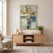 Contemporary Christian abstract cross framed canvas wall art featuring a luminous ivory cross with textured blue, beige, and gold brushstrokes displayed on a beige wall above a light wood console table in an organic modern living room.
