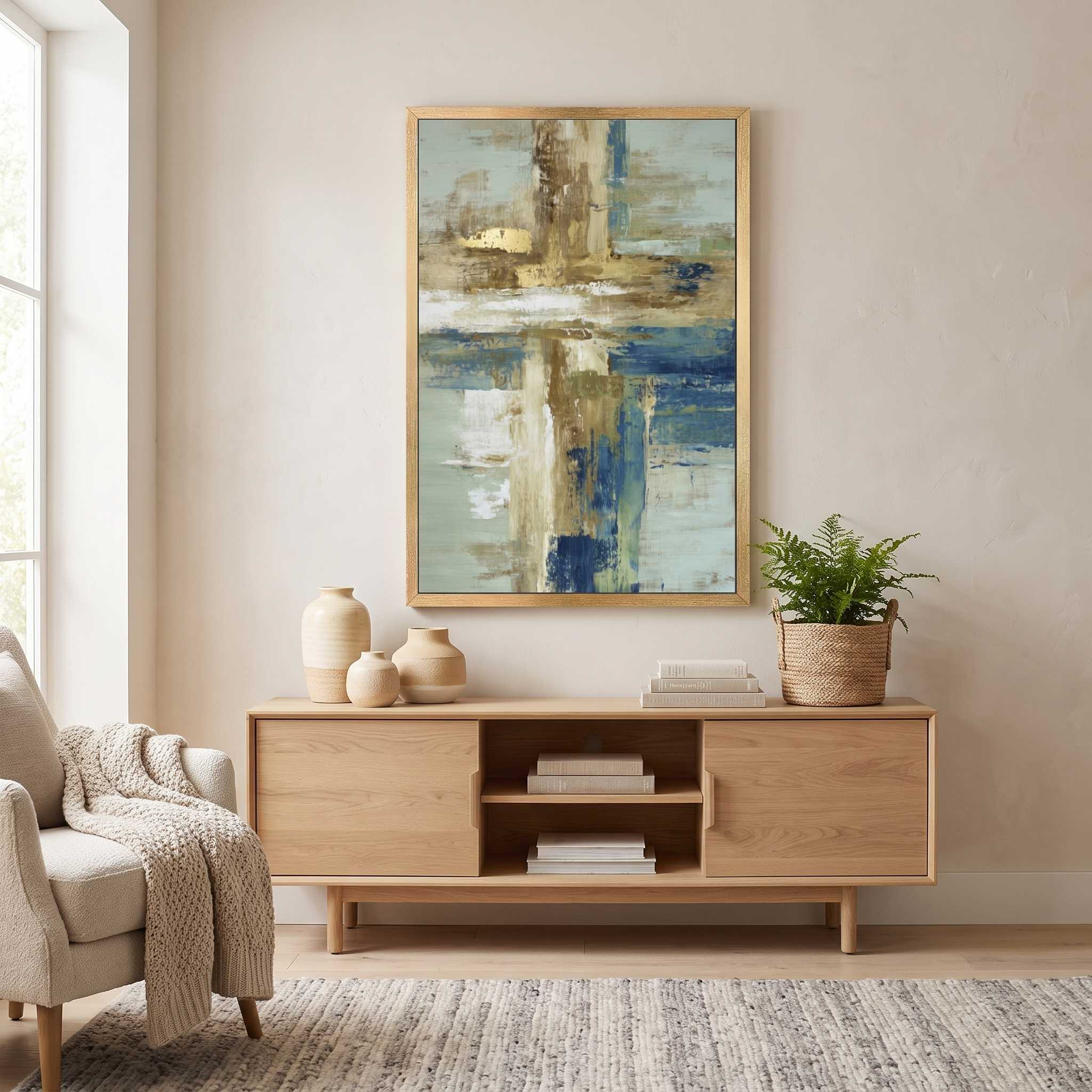 Contemporary Christian abstract cross framed canvas wall art featuring a luminous ivory cross with textured blue, beige, and gold brushstrokes displayed on a beige wall above a light wood console table in an organic modern living room.
