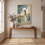 Contemporary Christian abstract empty tomb framed canvas wall art featuring a glowing open tomb motif in blue, beige, and gold displayed on a beige wall above a wooden console table in an organic modern entryway.