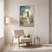 Contemporary Christian abstract empty tomb framed canvas wall art featuring a glowing open tomb motif in blue, beige, and gold displayed on a light wall above a cream armchair in a Scandinavian reading nook.