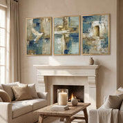 Contemporary Christian abstract 3-piece framed canvas wall art set featuring white dove, cross, and empty tomb motifs in blue, beige, and gold displayed on a beige wall above a stone fireplace mantel in an organic modern living room.