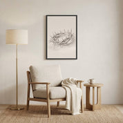 Minimalist Crown of Thorns line art in a black frame, styled in a cozy reading nook above a modern armchair with a floor lamp.