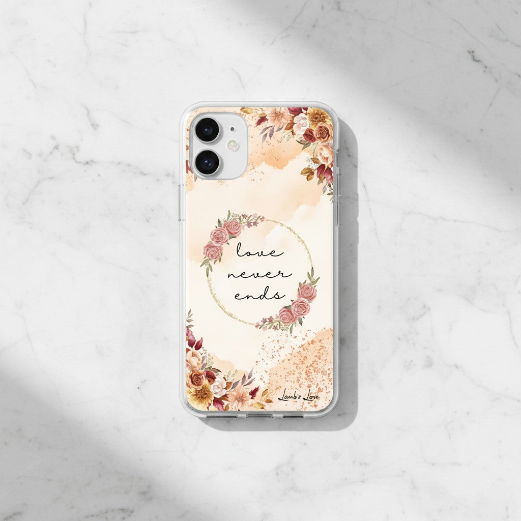 Minimalist Christian MagSafe iPhone case with 'Love Never Ends' 1 Corinthians 13:8 text and autumn floral design on a white marble background.
