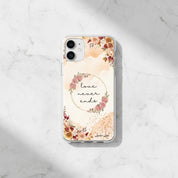 Minimalist Christian MagSafe iPhone case with 'Love Never Ends' 1 Corinthians 13:8 text and autumn floral design on a white marble background.