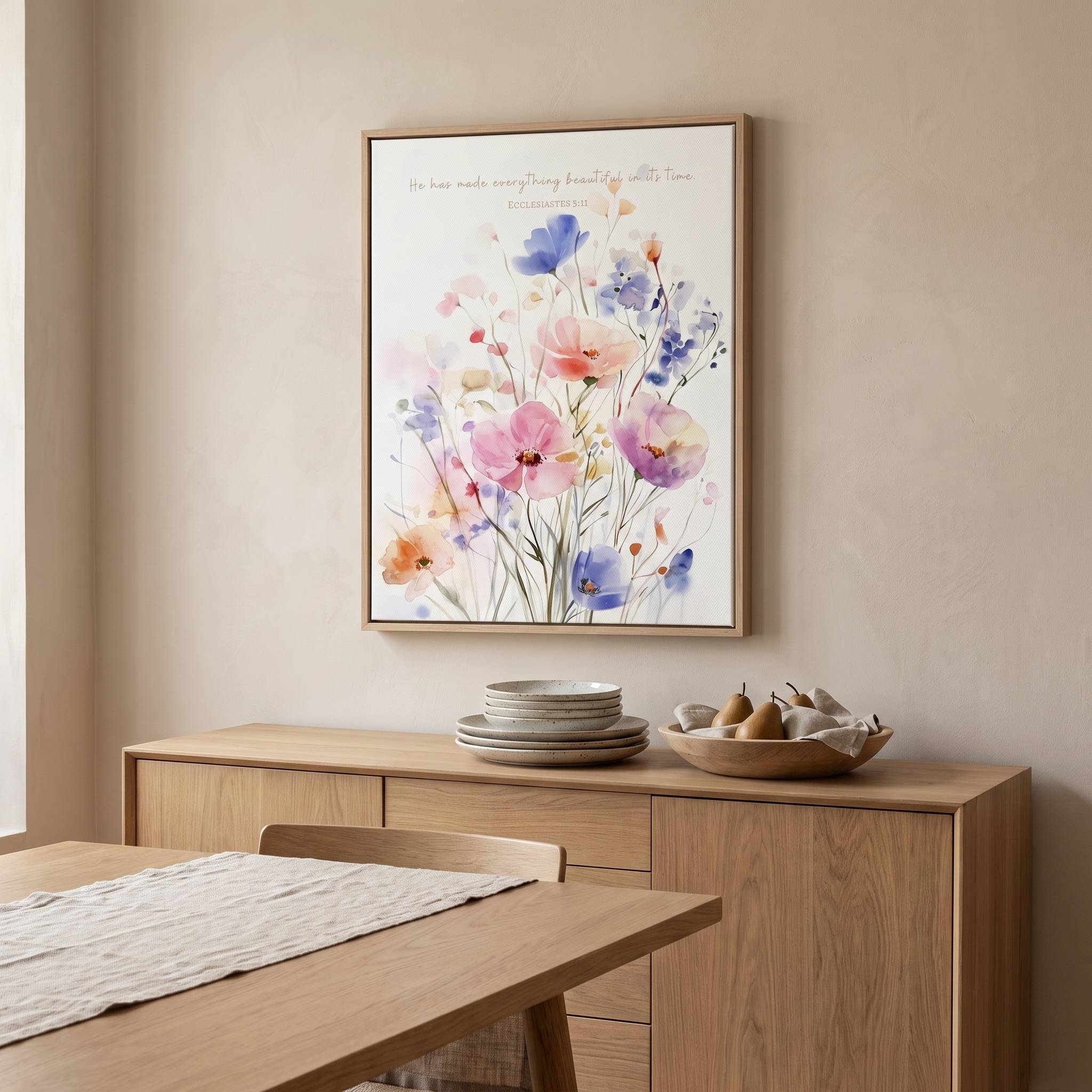 Ecclesiastes 3:11 watercolor floral Scripture wall art above a light wood dining room sideboard, with pastel wildflowers in pink, blue and purple.