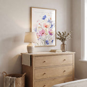 Ecclesiastes 3:11 floral Scripture wall art above a light wood bedroom dresser, featuring watercolor wildflowers in soft pink, blue, lavender and peach.