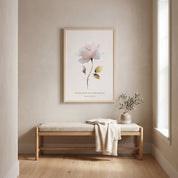 Framed vintage Christian floral wall art titled Lamentations 3:22–23 featuring a watercolor rose with "His mercies are new every morning", displayed on a beige wall above a wooden bench in a bright, minimalist entryway.