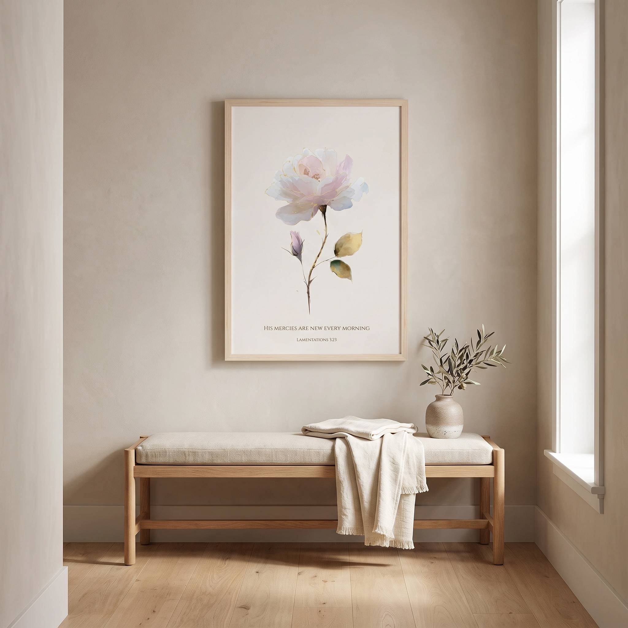 Framed vintage Christian floral wall art titled Lamentations 3:22–23 featuring a watercolor rose with "His mercies are new every morning", displayed on a beige wall above a wooden bench in a bright, minimalist entryway.