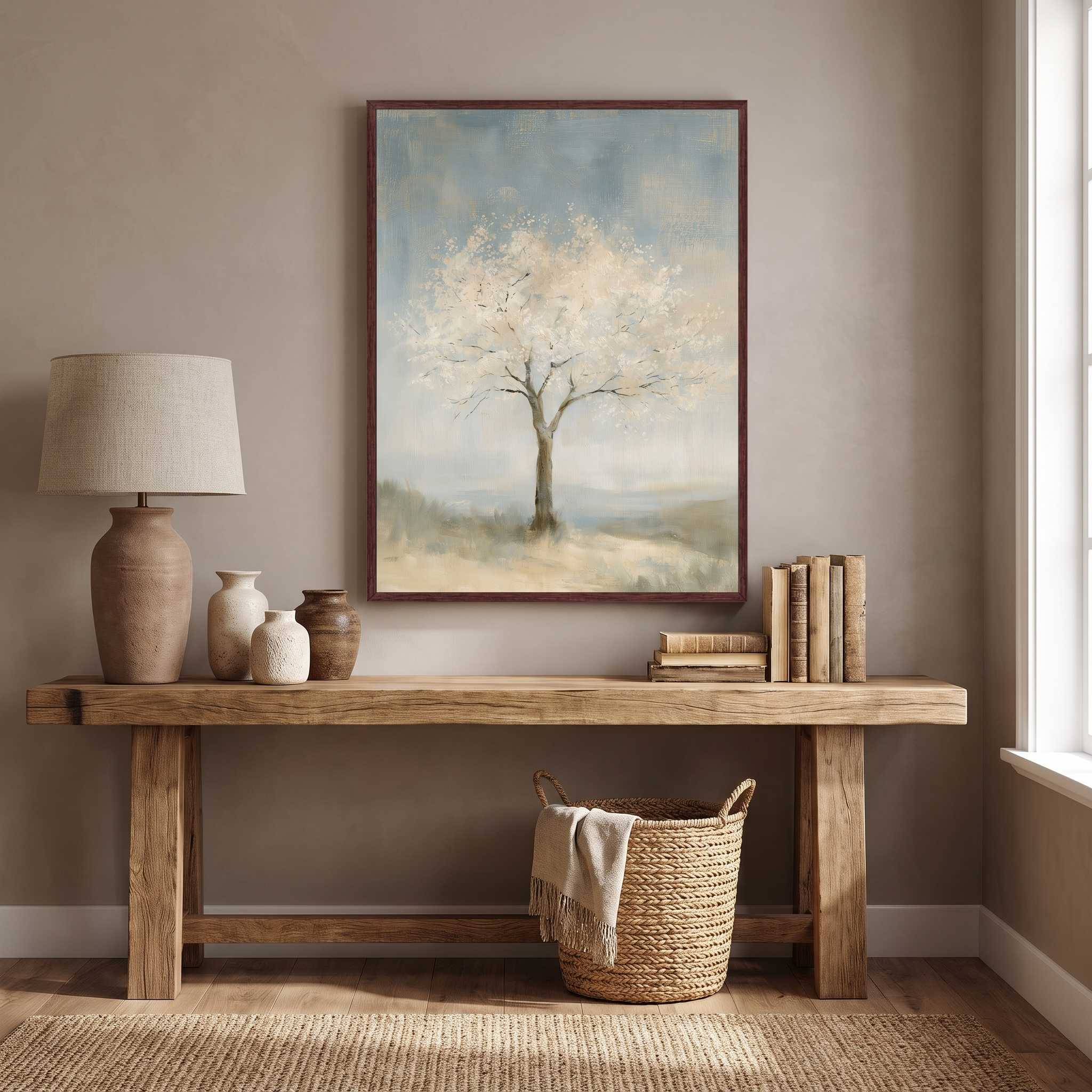 Faithful to His Word almond blossom tree Christian wall art in a dark wood frame above a rustic console with a table lamp, pottery, books and a woven basket.