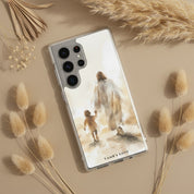 Christian Samsung Galaxy phone case with a watercolor design of Jesus walking with a child, styled on a beige surface with dried pampas grass and botanicals
