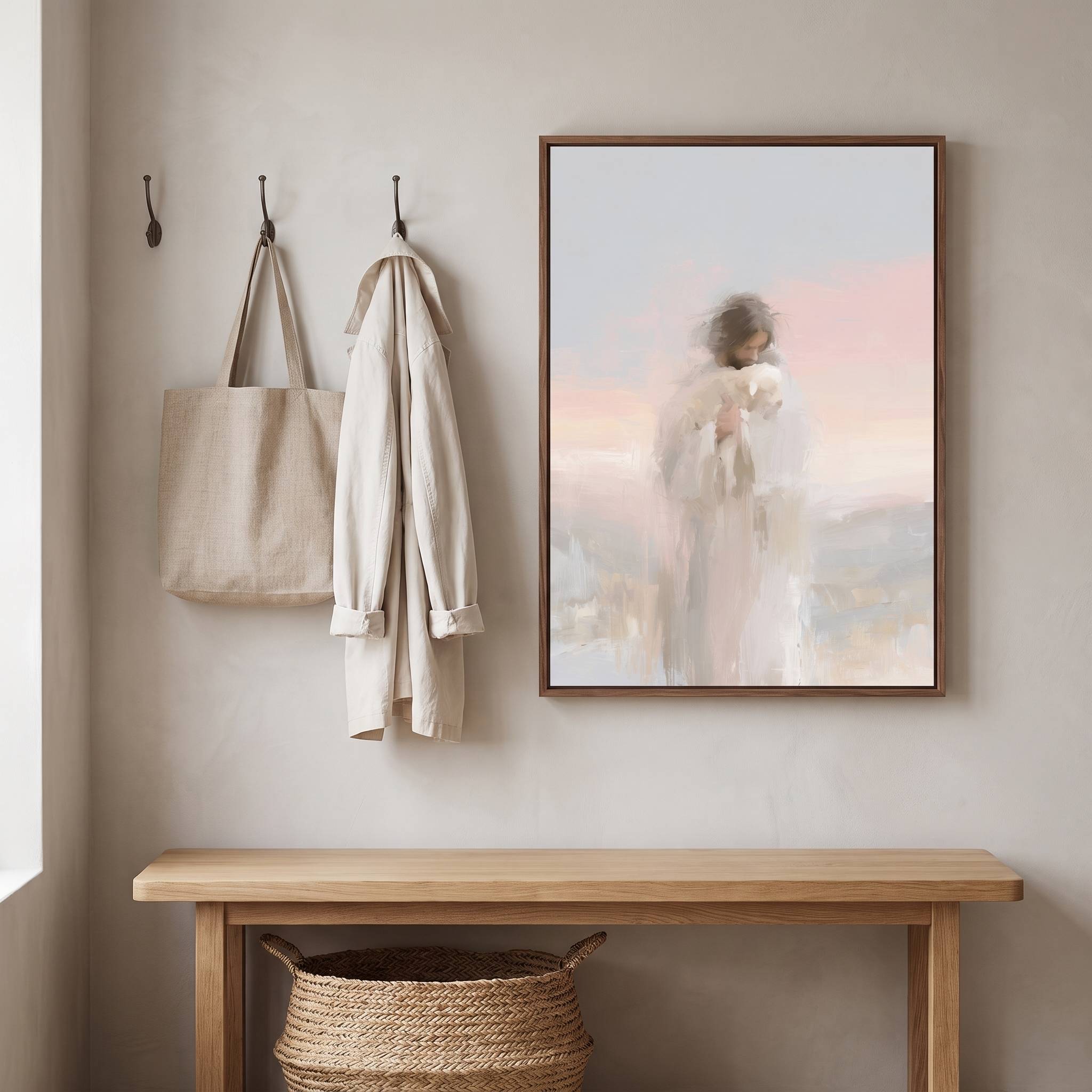 Framed watercolor Christian wall art of Jesus carrying a white sheep on a beige entryway wall above a wooden bench, styled with a woven tote and linen coat.