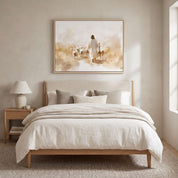 Good Shepherd Christian wall art from John 10:11 showing Jesus with His flock, framed above a bed in a warm neutral bedroom.