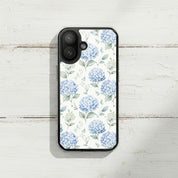 Grace in Bloom MagSafe® clear iPhone case featuring soft blue hydrangea floral artwork displayed on a rustic white wooden surface in a minimalist cottage-inspired setting
