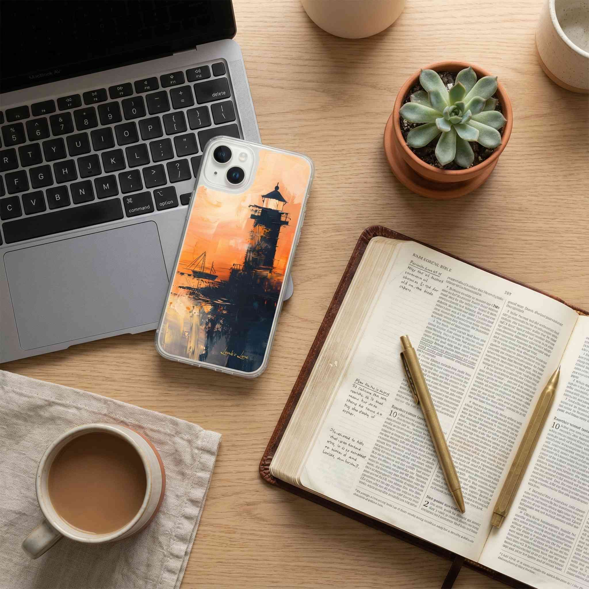 Laptop, phone with a scenic case, open book, pen, and coffee on a wooden desk.