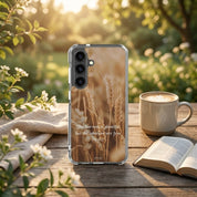 Phone case with wheat design and Bible verse on a table with a cup of coffee and open book.