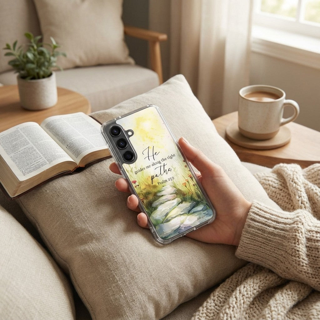 Person holding a Samsung galaxy phone with a scenic case on a cozy living room couch.
