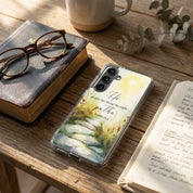 Samsung phone case with nature design and text on a wooden table with books and glasses.
