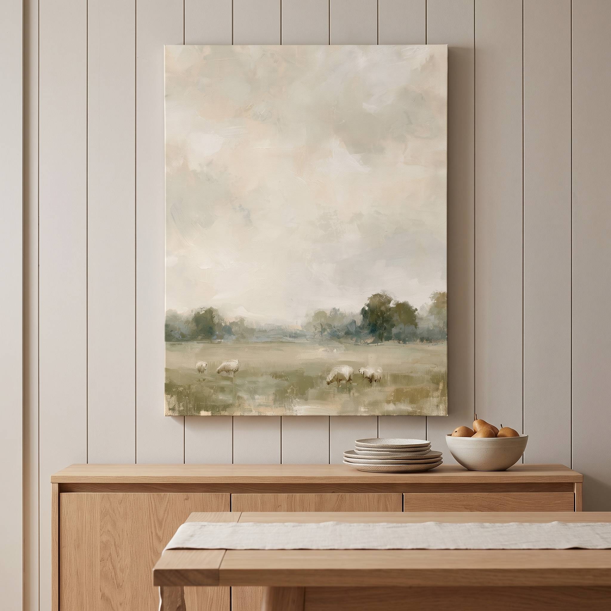 He Restores My Soul Christian sheep landscape canvas above a wooden dining room sideboard with stacked plates and a bowl beneath a soft cloudy sky scene.