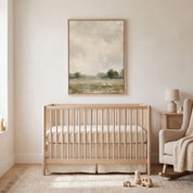 He Restores My Soul Christian sheep landscape wall art in a light wood frame above a wooden crib beside a cream rocking chair in a neutral nursery.