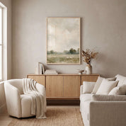 Framed He Restores My Soul Christian sheep landscape print above a wooden cabinet between a cream armchair and sofa in a neutral living room.