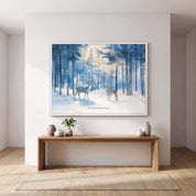A framed art print depicting two deer in a snowy forest hangs on a white wall above a wooden console table in a minimalist room setting.