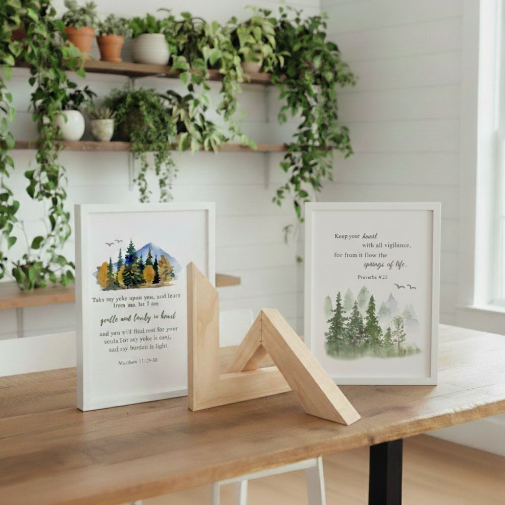 Framed prints with nature-themed designs on a wooden table, with plants in the background.