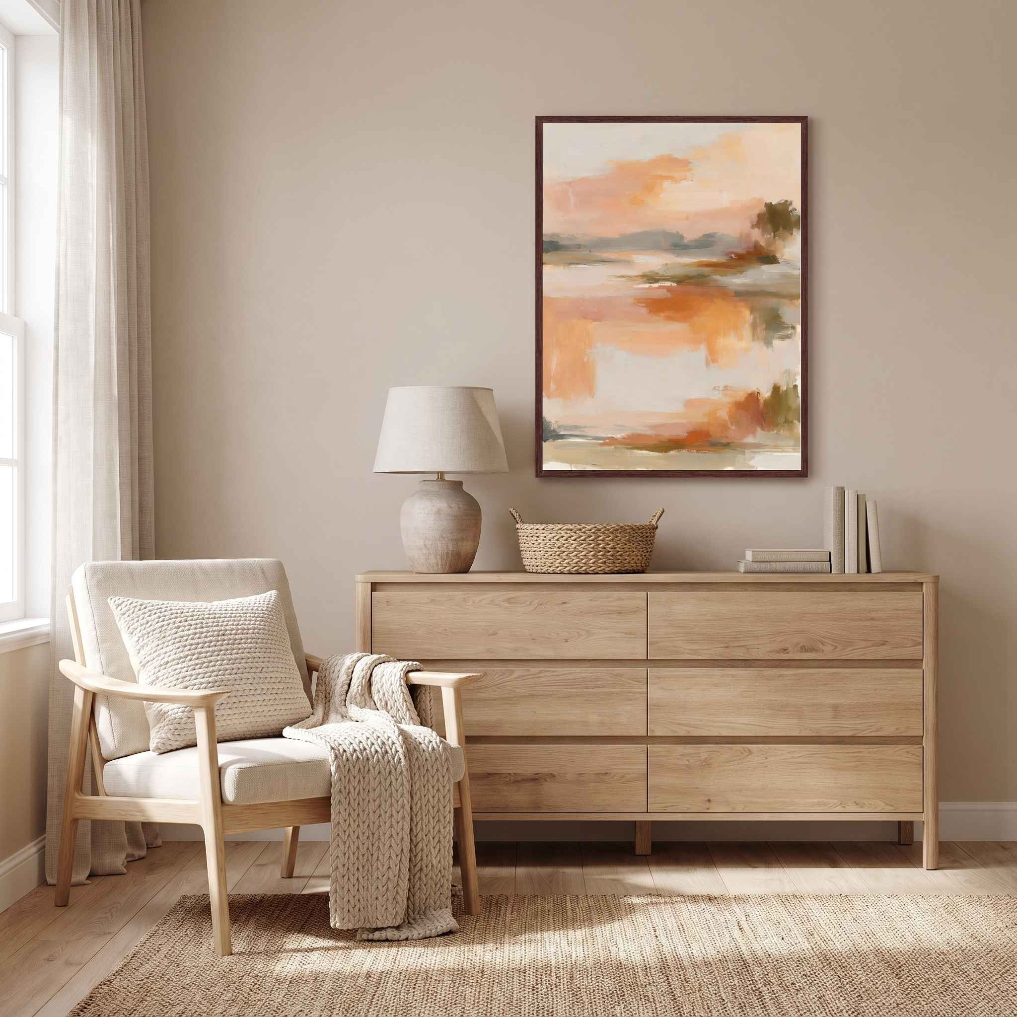 Framed abstract sunrise canvas wall art hanging above a light wood dresser next to an armchair in a serene warm-toned room.