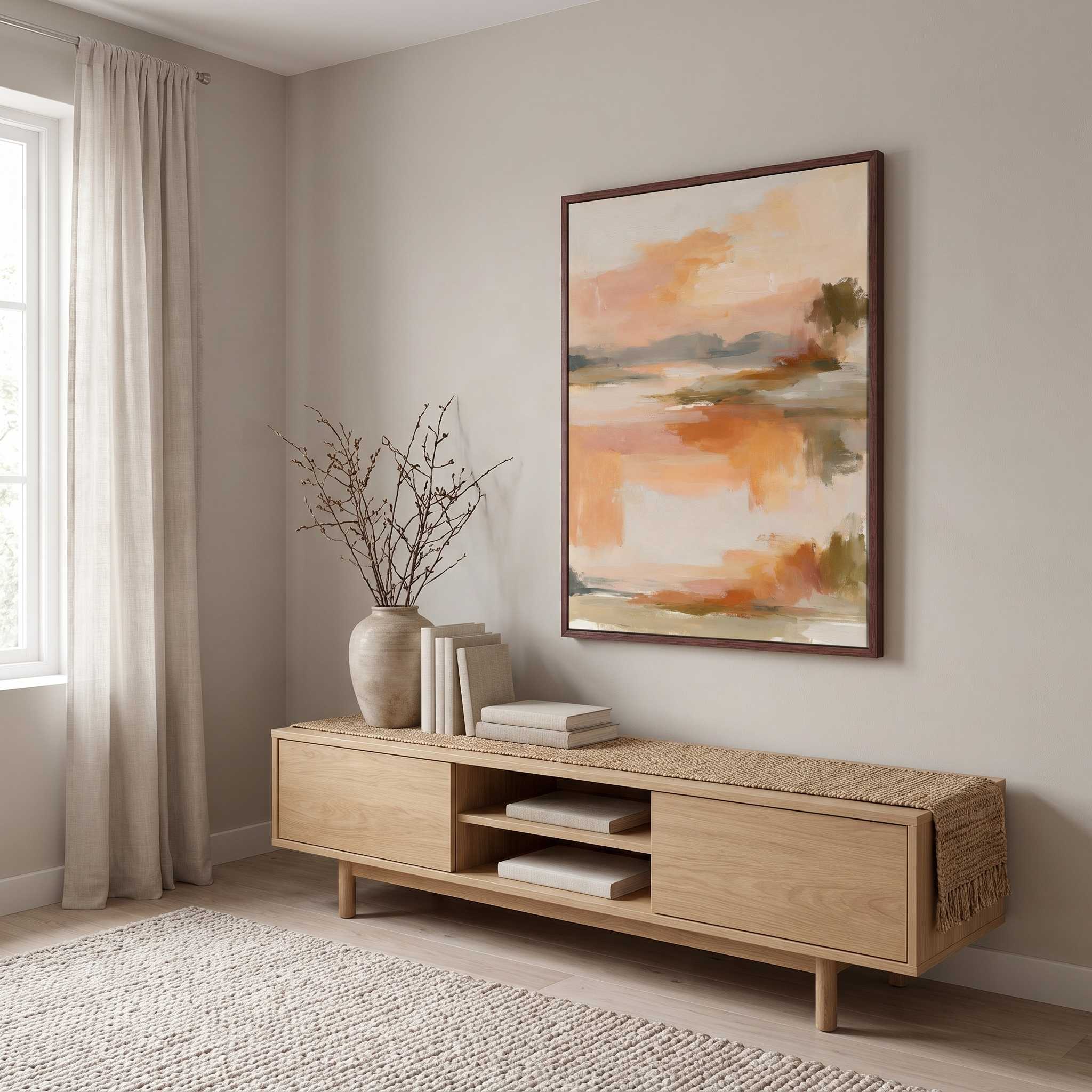Framed abstract sunrise canvas wall art hanging above a light wood console table in a bright Scandinavian living room near a window.