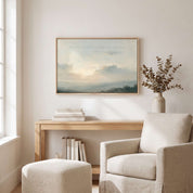 Framed vintage Lamentations 3:22-23 Christian landscape canvas wall art featuring a soft sunrise scene hanging on a light beige wall above a wooden console table, ceramic vase with eucalyptus, and a textured cream armchair with an ottoman in a cozy living room.