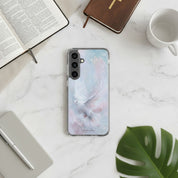 Holy Spirit Dove Christian Samsung phone case featuring a white watercolor dove on a soft blue and pink background, placed on a white marble desk next to an open Bible, a brown leather journal, a white coffee mug, and a monstera leaf.