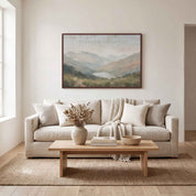 Framed vintage Christian landscape wall art titled I Lift Up My Eyes to the Hills, displaying a peaceful mountain view above a beige sofa in a soft organic modern living room.