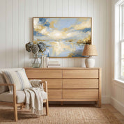Framed abstract Psalm 36:9 Christian landscape canvas wall art featuring golden light and soft blue water hanging on a white paneled wall above a light wood dresser and beige armchair in a bright bedroom.